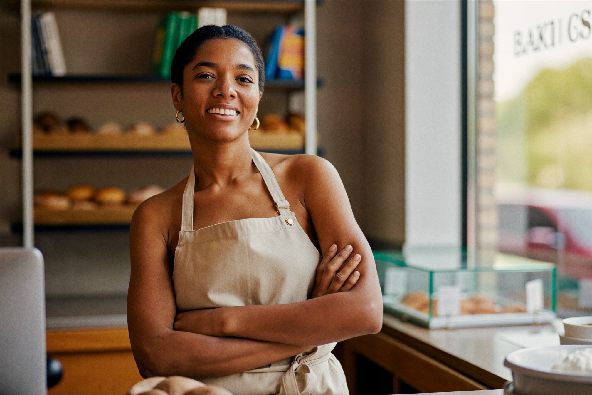 A small-business owner standing confidently in their place of business.